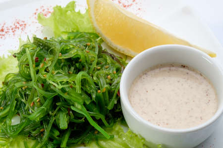 Seaweed salad with a lemon and a delicious sauce, cooked by experienced chefs in a restaurant on a white background.の写真素材