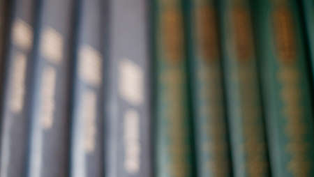 Old books on the shelf are not sharp background illuminated by the light from the window.の写真素材