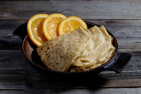 Orange with pancakes on wooden boards, covered with red cellar mysterious light.の写真素材