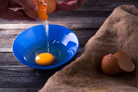 Egg in a blue plate on a wooden table illuminated side light.