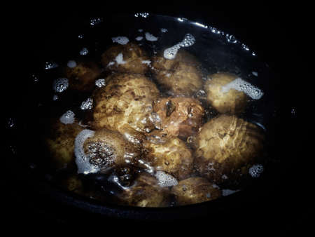 Cooking potatoes in their skins, cooked in a pot with artificial light basement.の写真素材