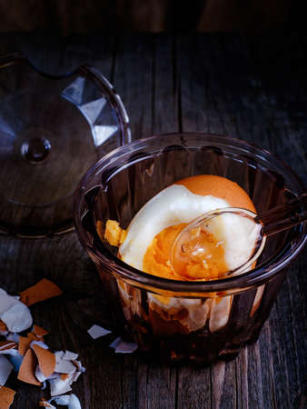 Boiled egg in cool on a wooden table illuminated by a red light basement.の写真素材