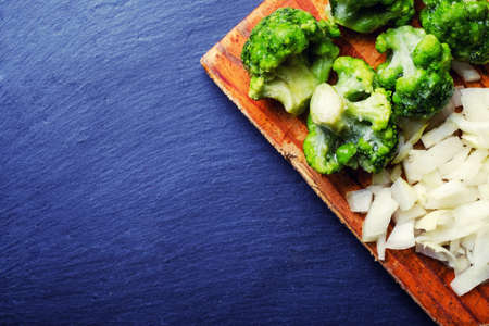 Fresh broccoli on a wooden board on a stone table.の写真素材