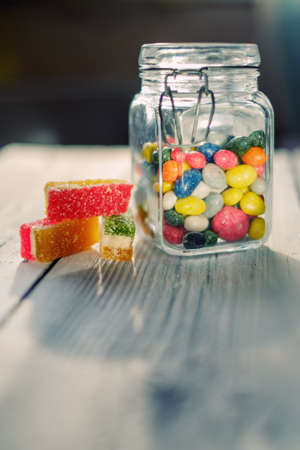 Yellow striped candy bag spilling its candies over a white wooden tableの写真素材