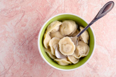Fresh homemade ravioli in a green plate on a pink stoneの写真素材