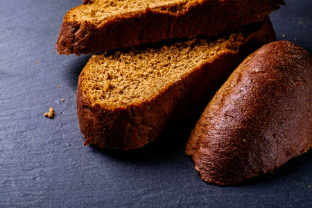 Delicious, fresh black bread on a black board in the studio.の写真素材