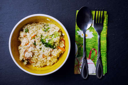 One serving of rice pudding on a black plate with ground cinnamon and sticks on a dark wooden table.の写真素材