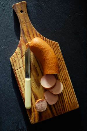 Uncooked sausages with mustard sauce on a wooden board