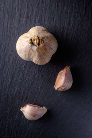 Organic red garlic cloves in a white bowl on the vintage wooden table, top viewの写真素材
