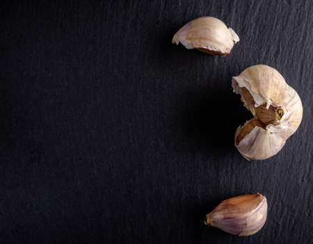 Organic red garlic cloves in a white bowl on the vintage wooden table, top viewの写真素材
