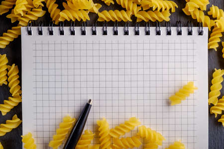 Beautiful yellow pasta with a notebook, lit studio lights.の写真素材