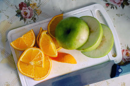 Sliced apple and orange on a white board top viewの写真素材