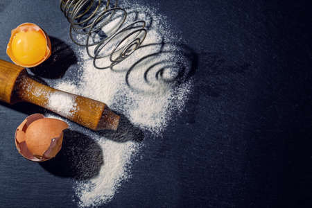 Dough preparation. Baking ingredients: egg and flour on the graphite board.の写真素材