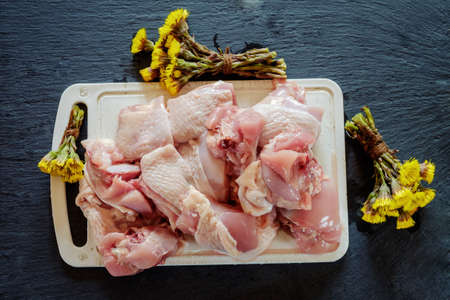 Raw meat chicken pieces on a white cutting board.の写真素材
