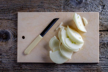 Onions circles, green onion with on board on wooden backgroundの写真素材