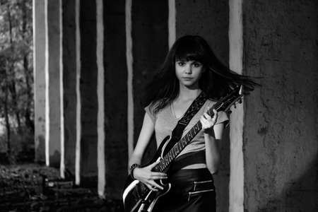 Beautiful young girl playing the guitar on the ruinsの写真素材