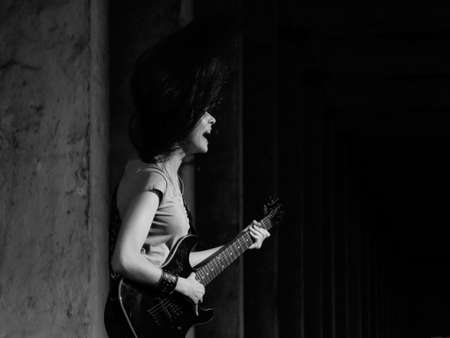 Beautiful young girl playing the guitar on the ruinsの写真素材
