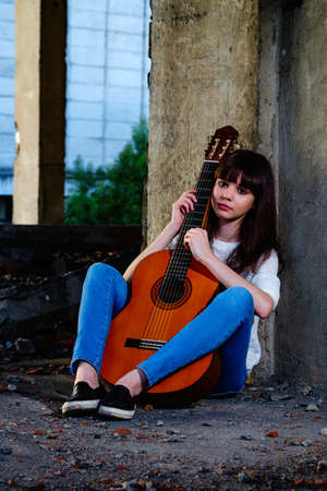 Beautiful young girl playing the guitar on the ruinsの写真素材