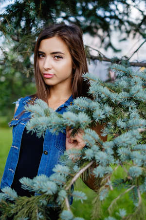 Beautiful sexy young brunette woman with long wavy hair thin slim figure perfect body and beautiful face make-up, wearing a black suit and vintage denim jacket. summer accessory, black backpackの写真素材