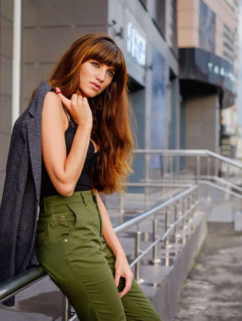 Beautiful red-haired young woman, pants, black top and bags walking on the streetの写真素材
