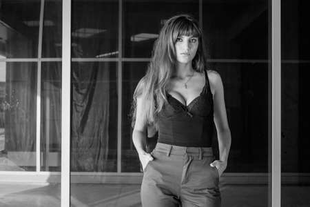 Beautiful red-haired young woman, pants, black top and bags walking on the streetの写真素材