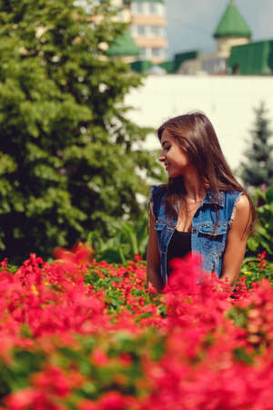 Beautiful sexy young brunette woman with long wavy hair thin slim figure perfect body and beautiful face make-up, wearing a black suit and vintage denim jacket. summer accessory, black backpackの写真素材