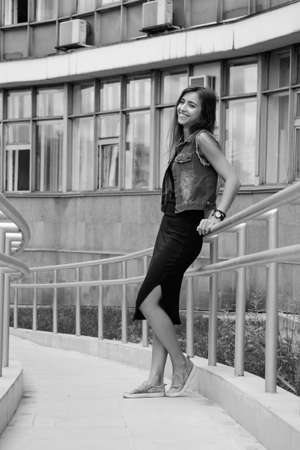 Beautiful sexy young brunette woman with long wavy hair thin slim figure perfect body and beautiful face make-up, wearing a black suit and vintage denim jacket. summer accessory, black backpackの写真素材