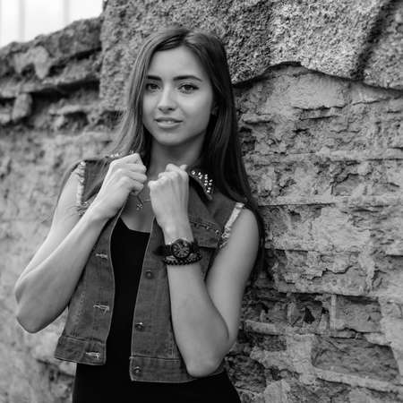Beautiful sexy young brunette woman with long wavy hair thin slim figure perfect body and beautiful face make-up, wearing a black suit and vintage denim jacket. summer accessory, black backpackの写真素材