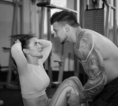 Girl and Men trainer engaged in simulator in gymの写真素材