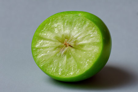 Green apple cut in half on a grey background, close-upの素材