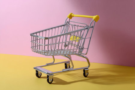 Empty shopping cart on a pink and yellow background with copy space.の素材