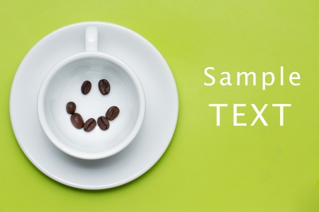 smiley face made from coffee beans in cup on green backgroundの写真素材