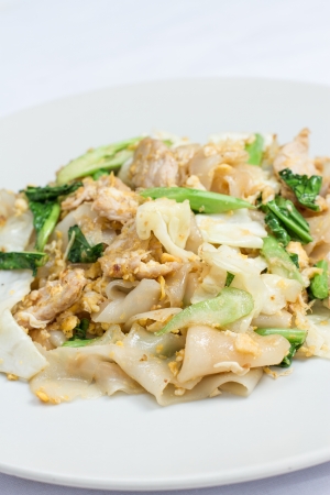 stir fired thin noodles with soy sauce and pork and Kale on white dishの写真素材