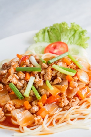 Closeup of spaghetti with meat, tomato sauce, and vegetables on white dishの写真素材