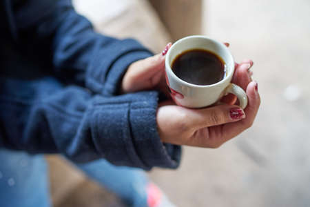 Girl holds coffee cup in her handsの写真素材