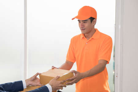 Deliverer giving package box to business man. SME start up conceptの写真素材