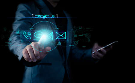 Concept Contact us or connected customer support hotline. businessman touching icon to communicate on a virtual screen,through a digital, global network. Icon (Email,Live Chat,Internet,Phone, Message)の写真素材