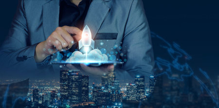 Startup business concept. Businessman holding a tablet, rocket launching and soar flying out from screen, starting a business, growing business, modern technology, hologram, network connection.の写真素材