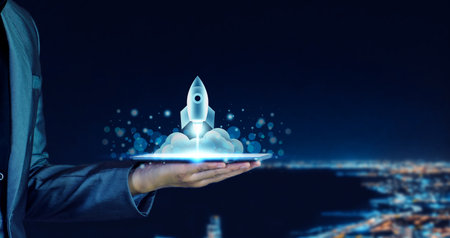 Startup business concept. Businessman holding a tablet, rocket launching and soar flying out from screen, starting a business, growing business, modern technology, hologram, network connection.の写真素材