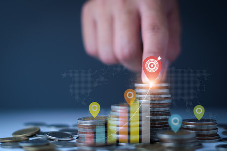Set financial goals concept. Businessman is tapping on top of coins, setting business and financial goals, saving money, investing money, growing business graph, increasing profit on investment.の写真素材