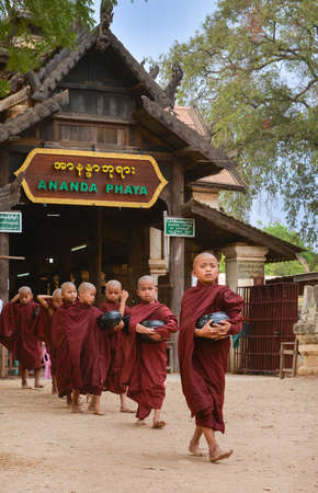Bagan, Myanmar - April 22, 2016 : Little Buddhist  monks walking in front of Gate of Ananda templeのeditorial素材