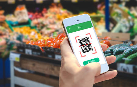 Hand holding smartphone to scan QR code payment , online shopping , cashless technology concept. 