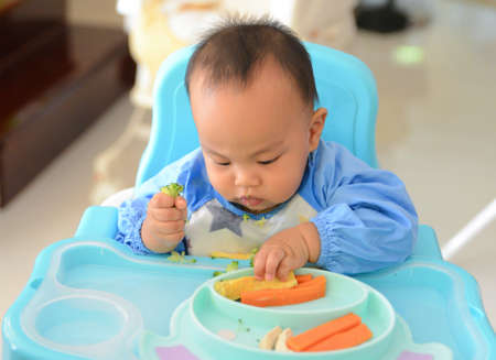 Asian baby boy 6 months old eating with Baby Led Weaning (BLW) method, Baby eat by himself, Self-Feedingの写真素材