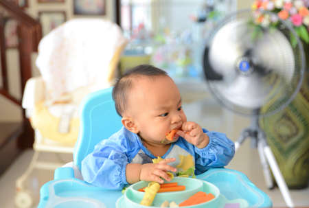 Asian baby boy 6 months old eating with Baby Led Weaning (BLW) method, Baby eat by himself, Self-Feedingの写真素材
