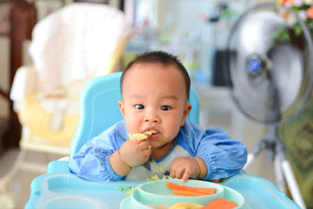 Asian baby boy 6 months old eating with Baby Led Weaning (BLW) method, Baby eat by himself, Self-Feedingの写真素材