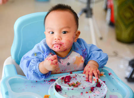 Happy eating Asian baby boy, 7 months old eating with Baby Led Weaning (BLW) method, Baby eat by himself, Self-Feedingの写真素材
