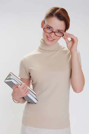 beautiful girl with books and wearing glasses in a beige jacketの写真素材