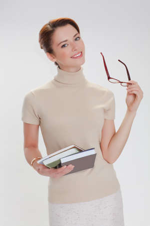 beautiful girl with books and wearing glasses in a beige jacketの写真素材