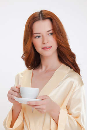 nice girl in beige home dressing gown with a cup of coffeeの写真素材