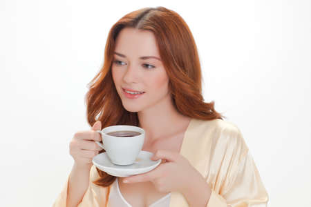 nice girl in beige home dressing gown with a cup of coffeeの写真素材